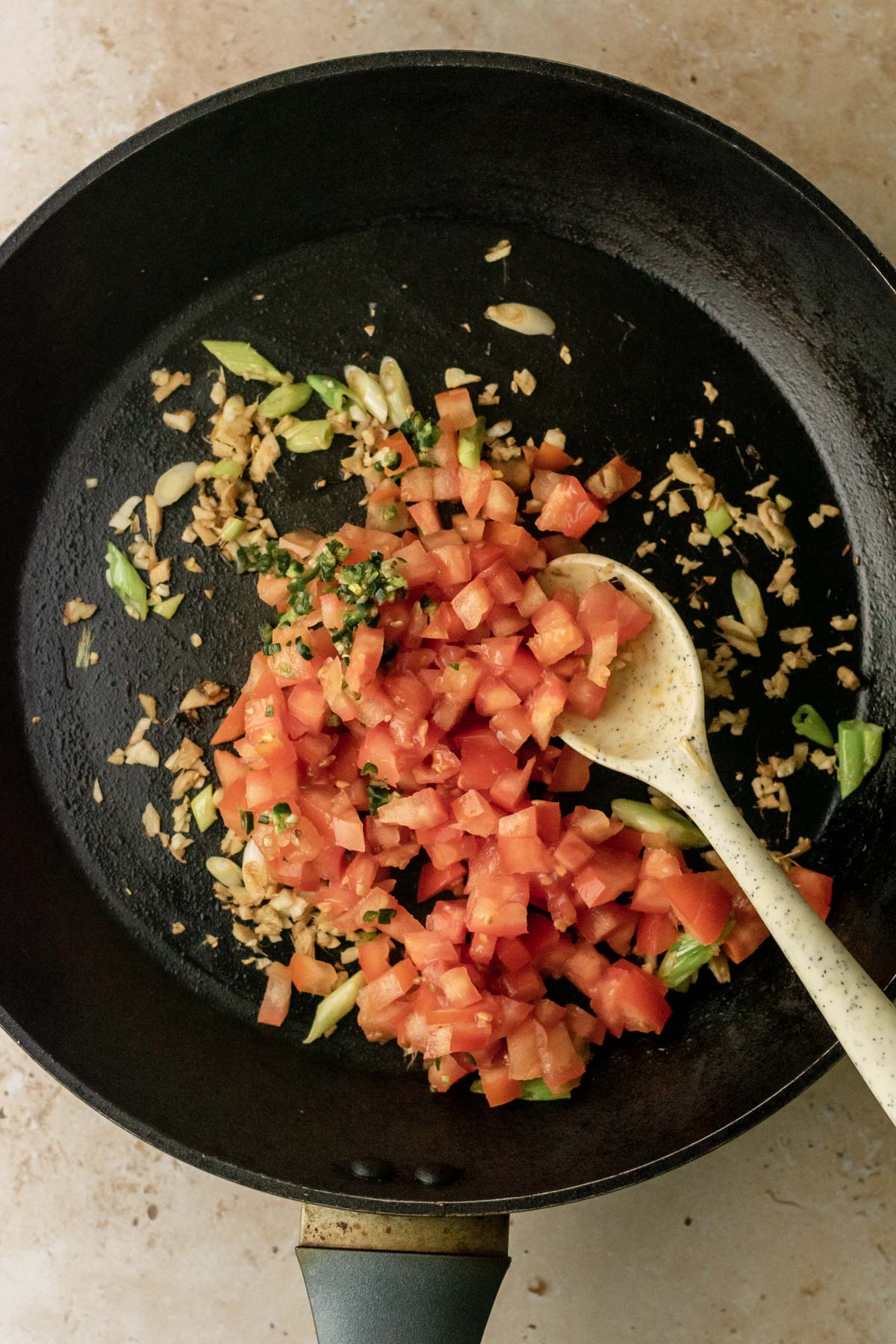 tomatoes and green chillies in a frying pan with other ingredients