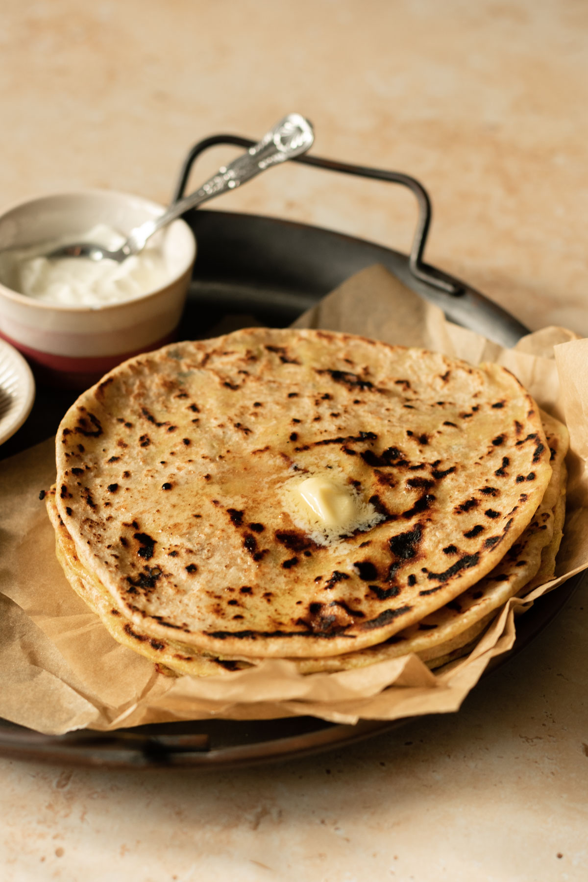 a stack of aloo paratha topped with ghee