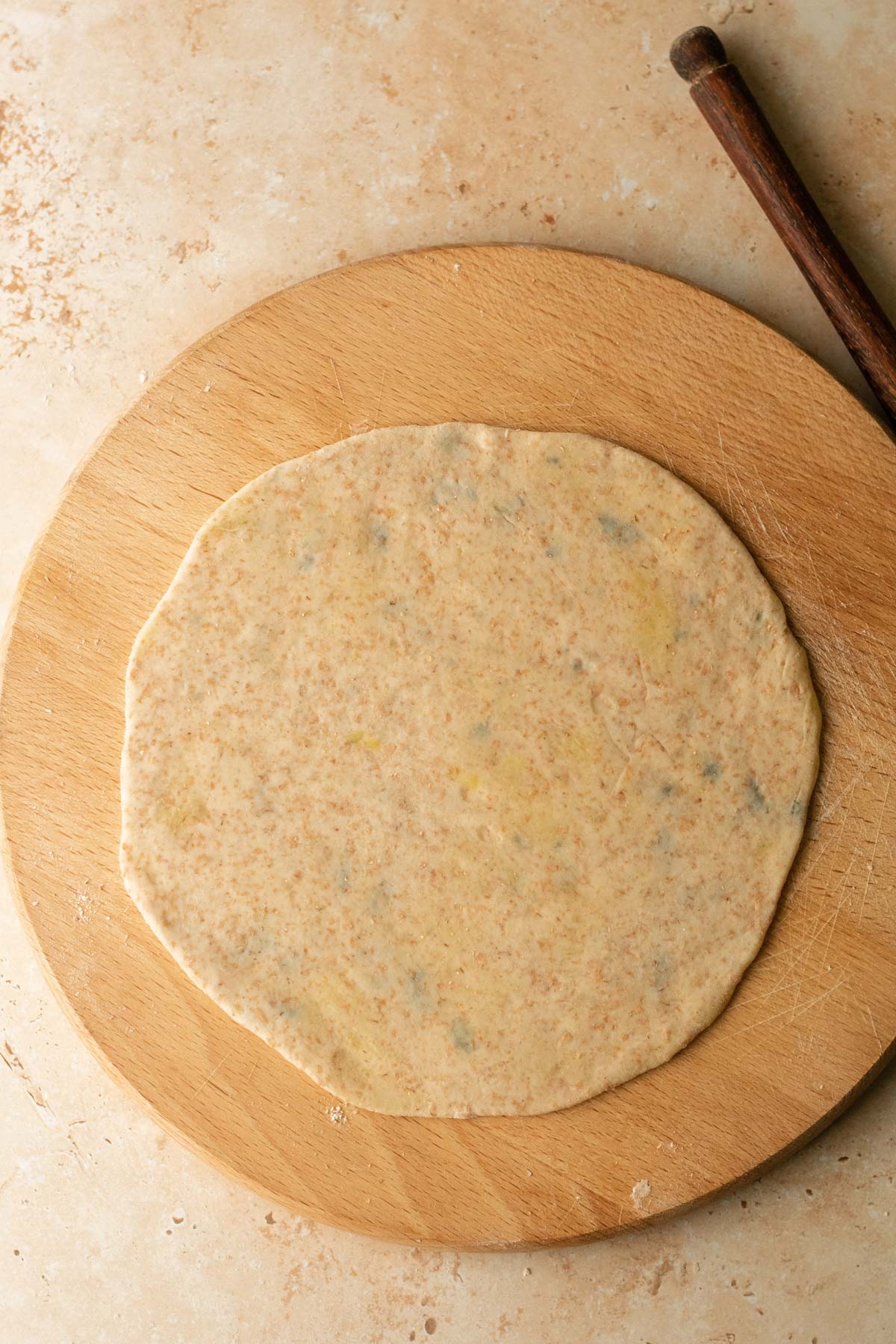 a rolled out aloo paratha ready to be cooked