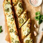 two slices of garlic bread topped with cheese and sliced jalapenos