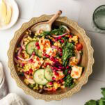 a bowl of salad with halloumi, broccoli and pearl couscous, topped with pomegranate seeds