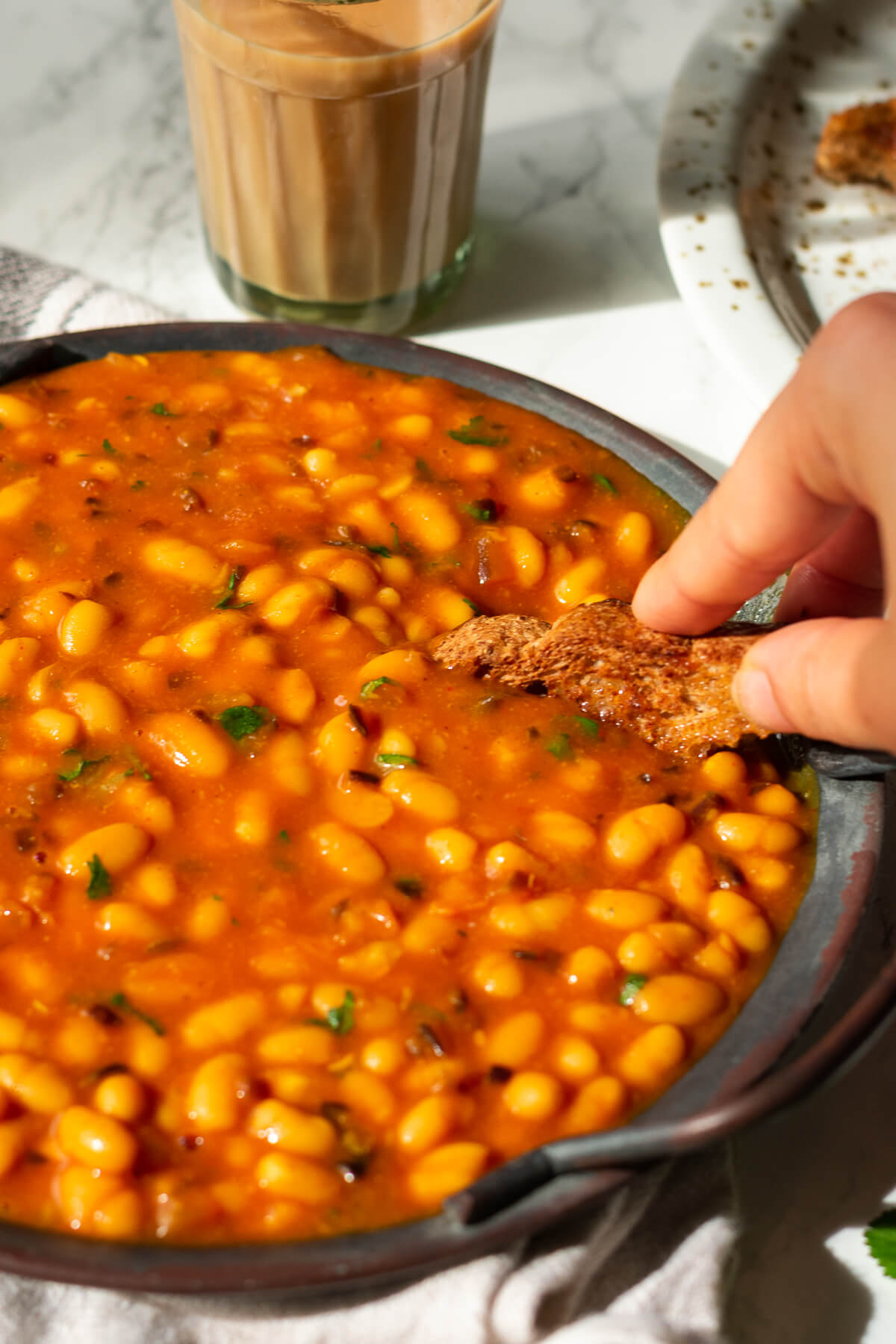 a peice of toast being dipped into a plate of masala baked beans