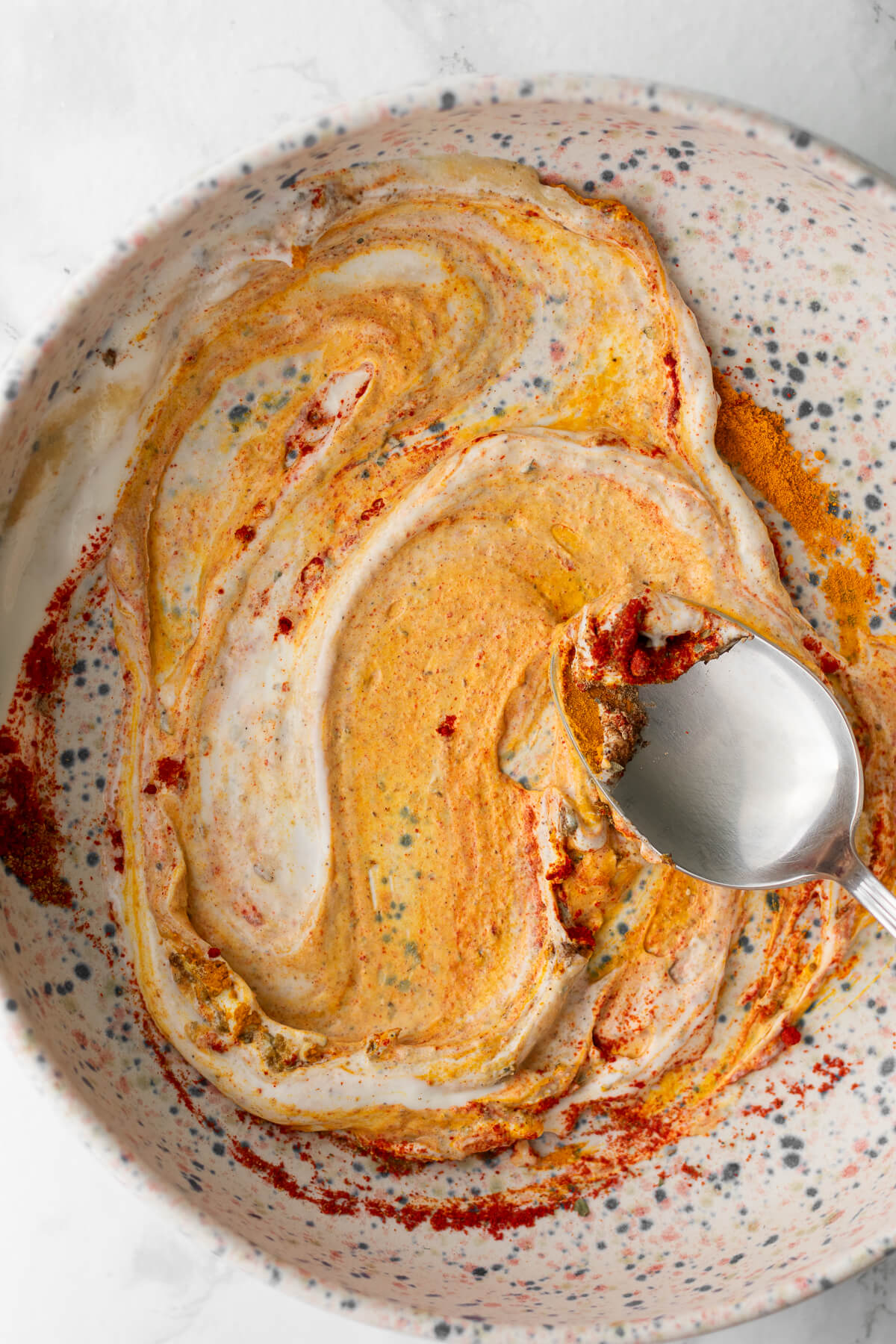 a bowl of yogurt being mixed with spices