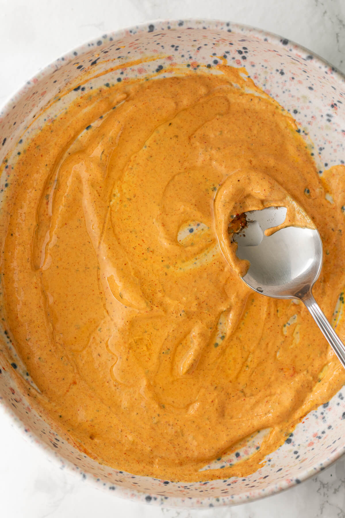 a bowl of yogurt marinade topped with sizzling oil