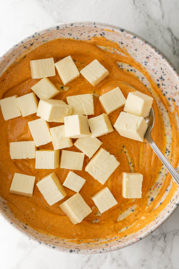 a bowl of spicy yogurt marinade topped with paneer cubes