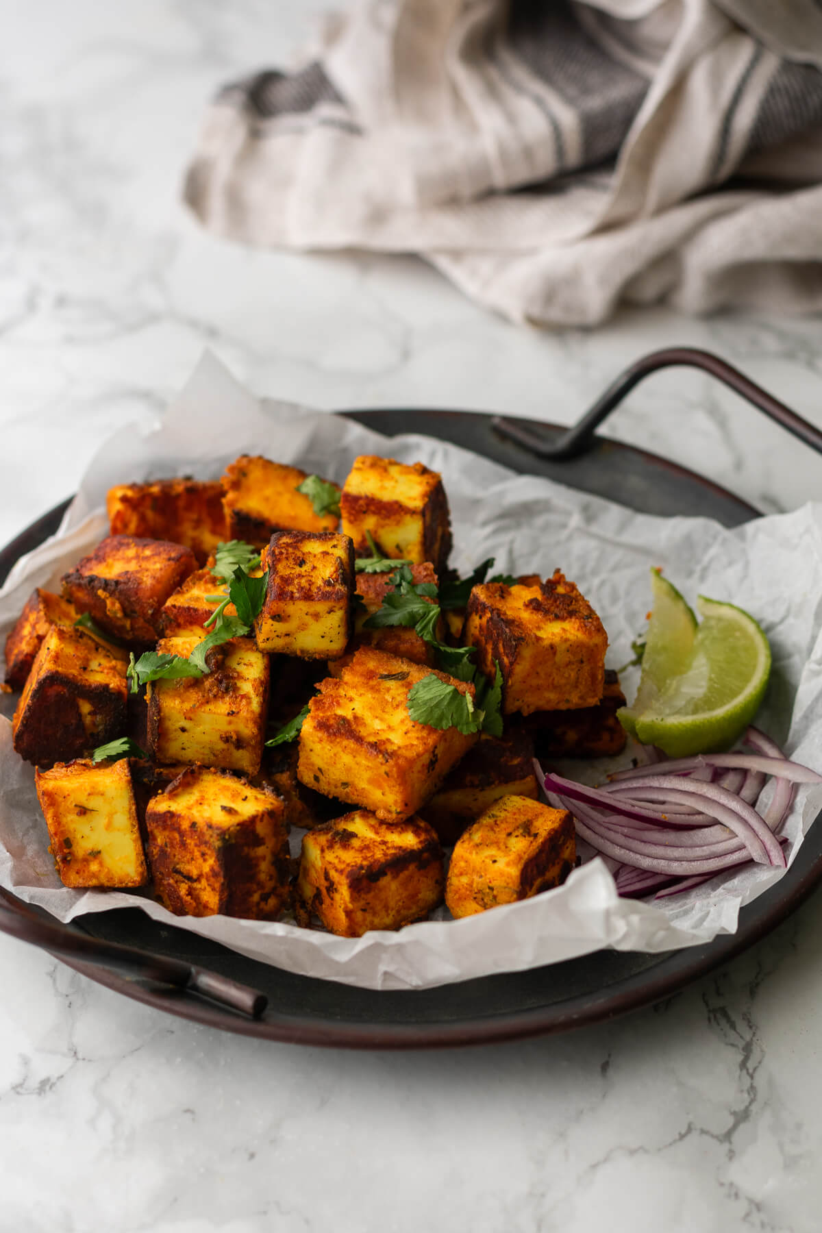 a plate piled high with crispy pan fried paneer tikka