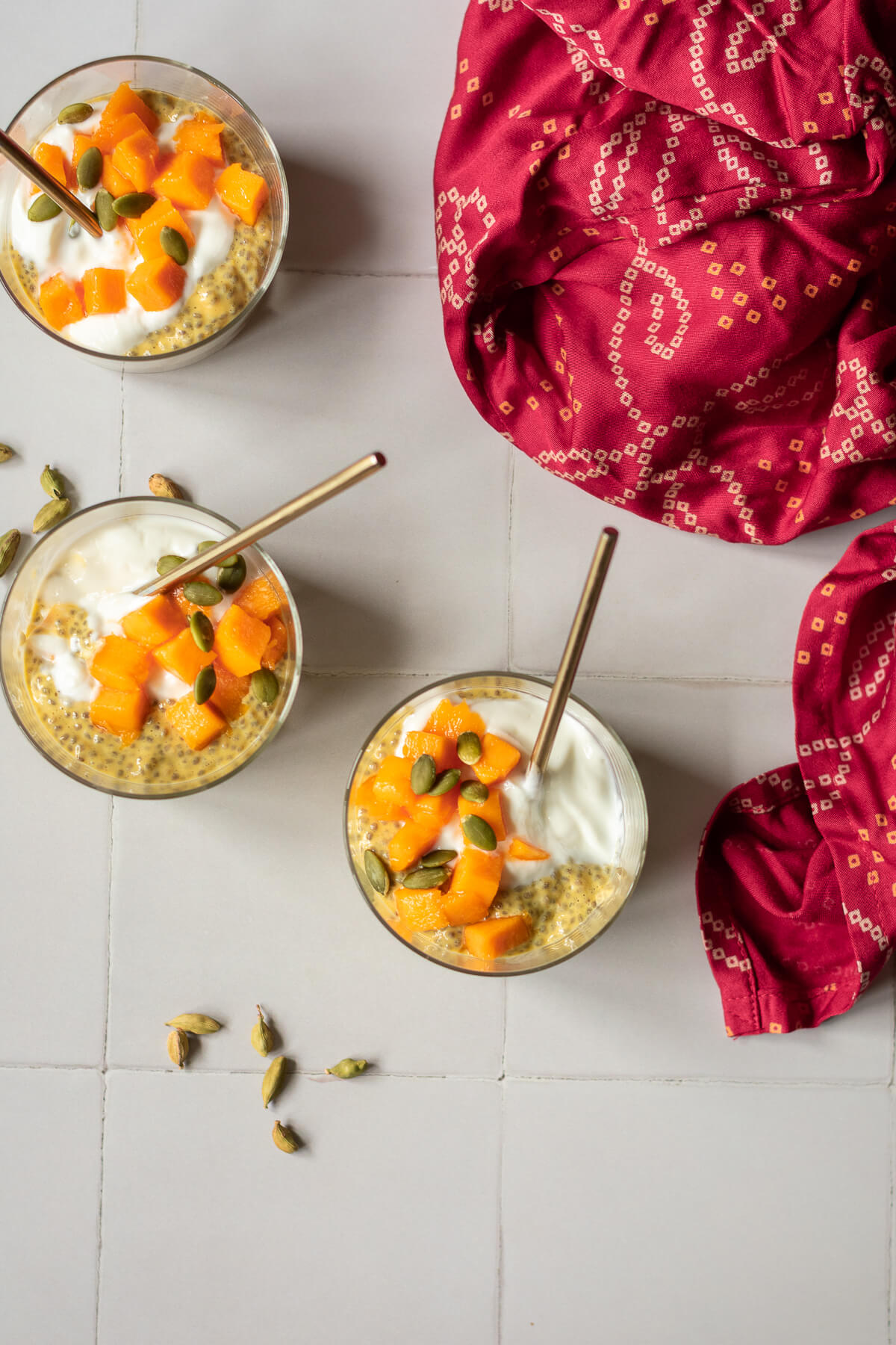 three jars of mango chia pudding with spoons