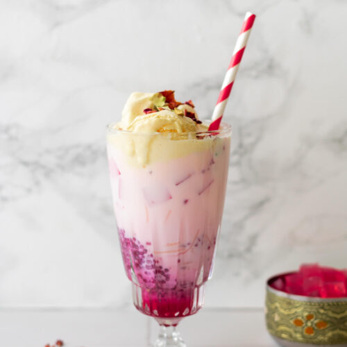 a glass of rose falooda topped with ice cream