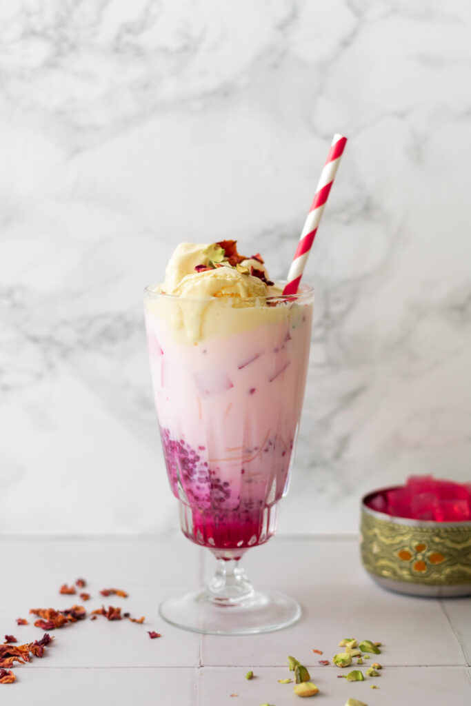 a glass of rose falooda topped with ice cream